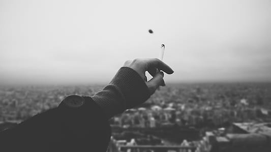 grayscale photo of person holding single cigarette thumbnail