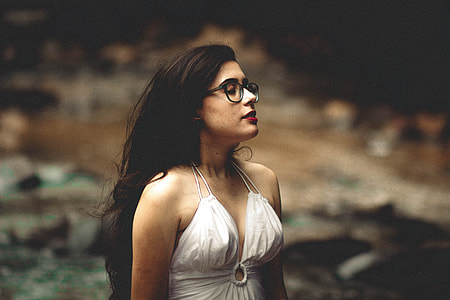 women in white top standing in front of body of water thumbnail