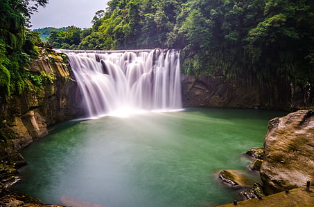 waterfalls surrounded by green trees during daytime thumbnail