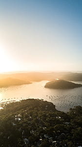 bird's eye view of islet surrounded with hills under calm sky thumbnail