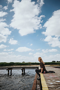 Beautiful blonde woman on a wooden pier by the lake thumbnail