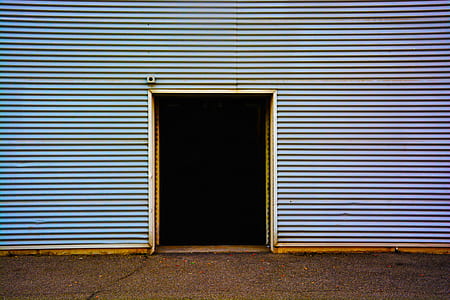 open door in blue corrugated steel wall during daytime thumbnail