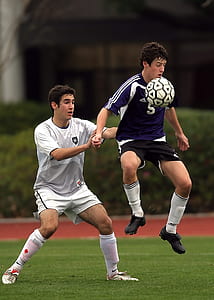 Two Men Playing Soccer at Soccer Field Near Green Plants during Daytime thumbnail