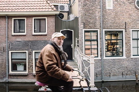 man in brown leather jacket riding bicycle thumbnail