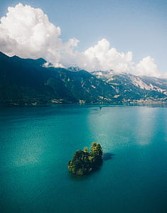 island with green trees under blue cloudy skies thumbnail