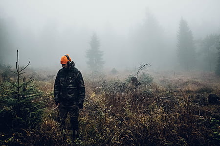 man in black jacket standing on brown grass field thumbnail