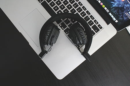 black wireless headphones on top of MacBook Pro thumbnail
