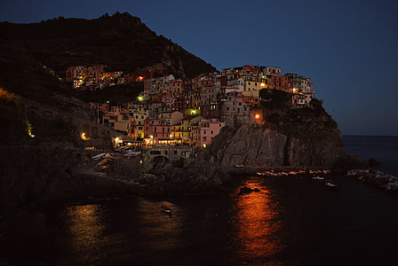 buildings on cliff near body of water at night thumbnail