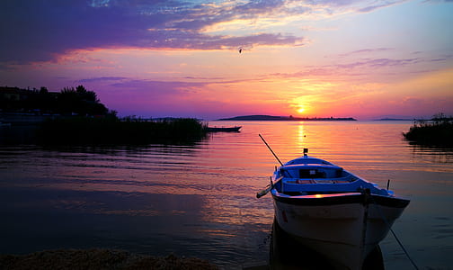 photo of white row boat on body of water during sunset thumbnail