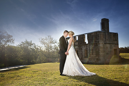 bride and groom standing on grass field while holding hands thumbnail