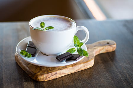 ceramic teacup filled with coffee and chocolate bars during daytime thumbnail