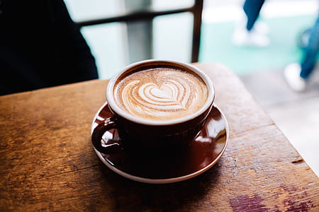 black ceramic coffee cup filled with brown liquid on brown wooden table thumbnail