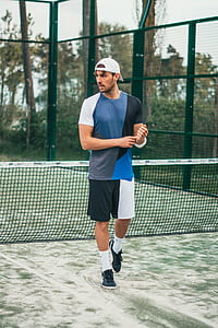 man in blue and white crew-neck shirt standing in front of tennis net thumbnail