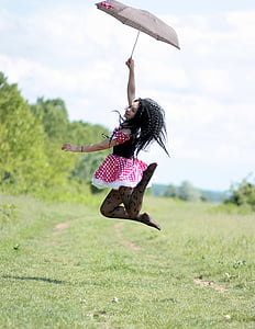 woman holding umbrella jumping on green grass field thumbnail