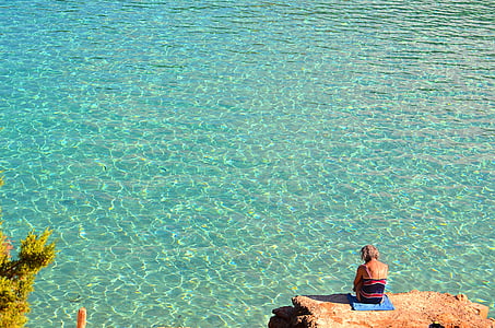woman wearing black and red top near body of water thumbnail