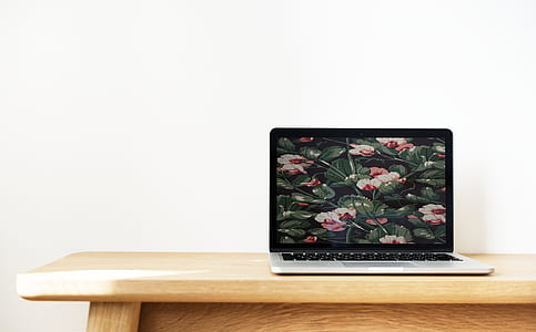 turned on black and gray laptop computer displaying flowers on brown wooden table thumbnail