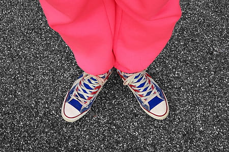 person wearing pink bottoms and blue-and-red lace-up sneakers on gray surface thumbnail