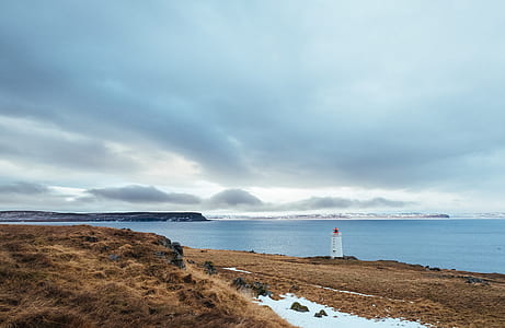 lighthouse beside body of water during daytime thumbnail