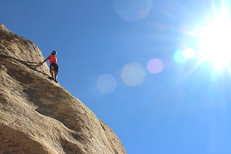 person in pink top and black bottom trekking mountain thumbnail