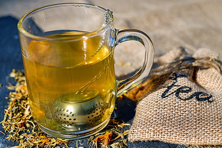 yellow liquid filled clear glass mug beside gray drawstring pouch thumbnail