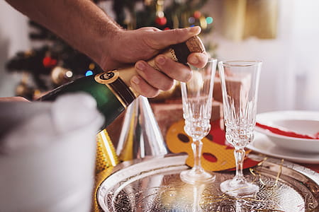 Man Opening Champagne In Room Decorated For Christmas thumbnail