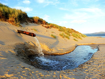 pipe producing liquid on sandy shore thumbnail