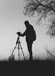 silhouette of man holds tripod camera at daytime thumbnail
