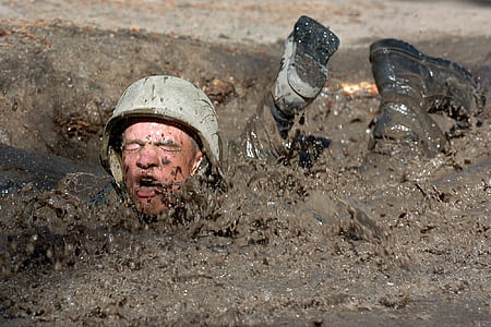 soldier lying prone in mud during daytime thumbnail