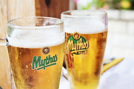 two clear Mythos drinking glass filled with beer thumbnail