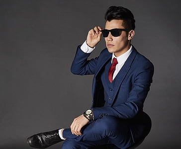 man sitting wearing blue suit and sunglasses thumbnail