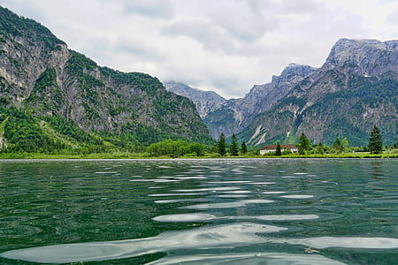 mountain beside body of water under cloudy sky thumbnail