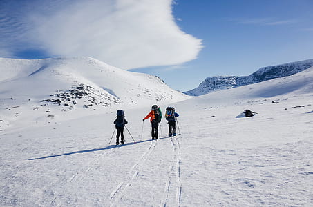 three person walking on snow covered field during daytime thumbnail