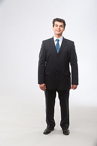 man wearing black suit jacket and dress pants standing inside white room thumbnail