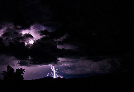 silhouette of trees with distance to lightning bolt landscape photo thumbnail