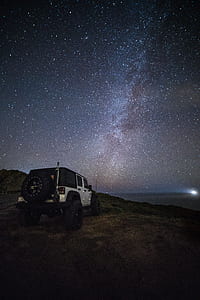white Jeep Wrangler 5-door SUV under gray starry sky during night time thumbnail