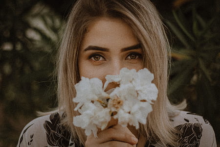 woman holding white petaled flowers covering her mouth thumbnail