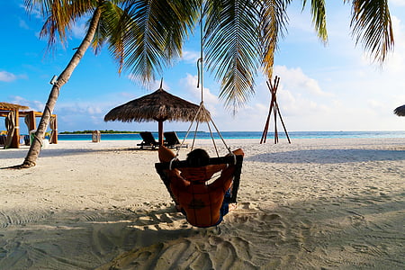 man lying on hammock facing sea thumbnail