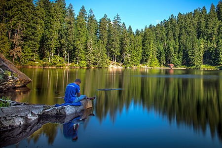 man in blue shirt sitting on rock floating on water during daytime thumbnail