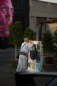 person standing while holding poster near building thumbnail