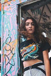 woman leaning on white wooden door framed wearing black and multicolored dragon printed crew-neck t-shirt thumbnail