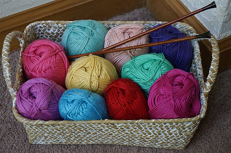 assorted-color yarn rolls in basket with hooks thumbnail