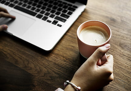 person holding mug while using MacBook thumbnail