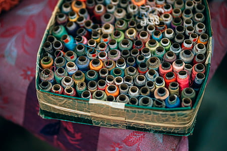 assorted-color threads in box on floral textile thumbnail