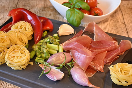 sliced meat, pasta, and vegetables on chopping board thumbnail