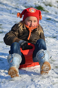 girl wearing brown zip-up jacket blue denim jeans on red sled thumbnail