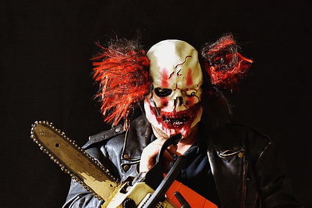 person in Halloween costume holding orange, gray, and white chainsaw thumbnail