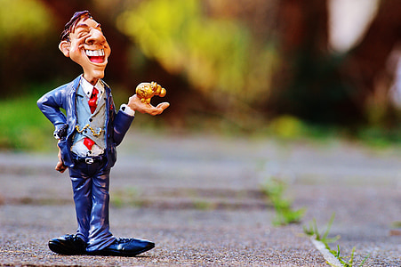 man wearing blue suit and tie holding brass-colored figurine thumbnail