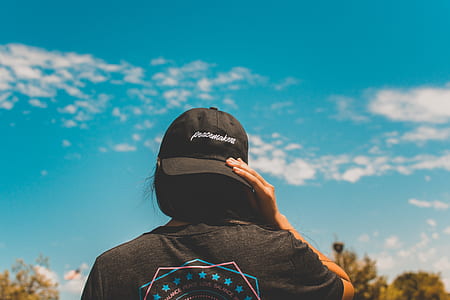 close-up photo of woman wearing black fitted cap under blue sky during daytime thumbnail