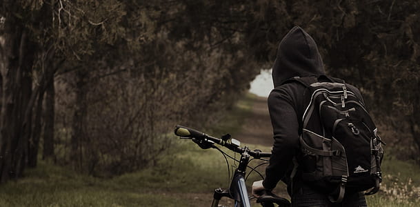 man wearing black pullover hoodie walking on dirt road thumbnail