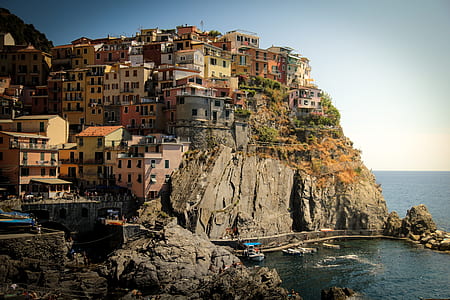 houses on gray mountain rock near the body of water during daytime thumbnail